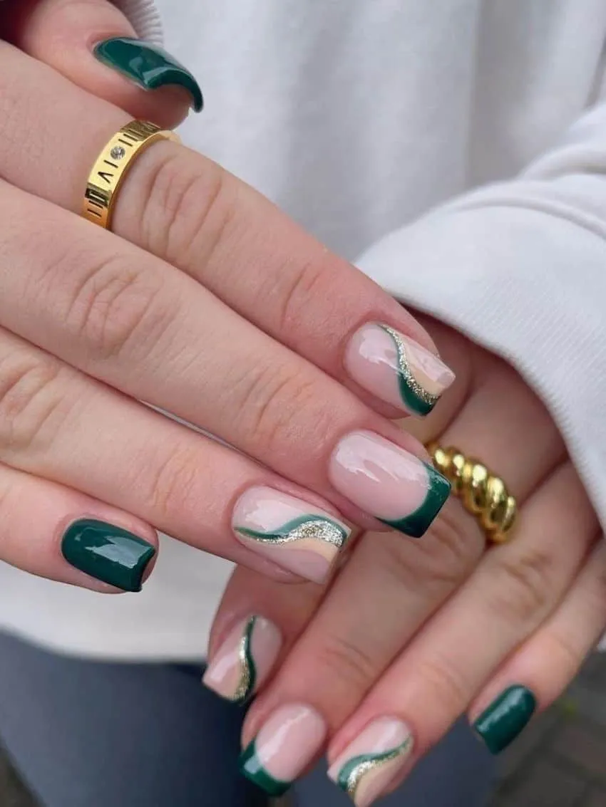Manicure with solid emerald green and abstract green and silver glitter swirl nail art.